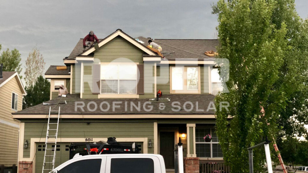 Professional roofing contractors installing new shingles on residential home roof