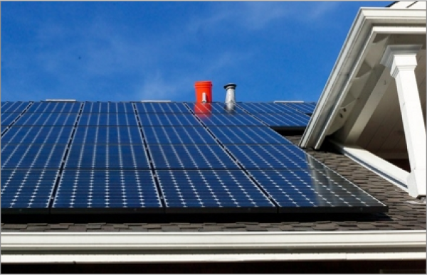 Blue solar panels installed on residential house roof against clear blue sky