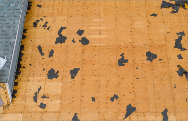 Damaged orange roof with peeling black tar patches and missing shingles