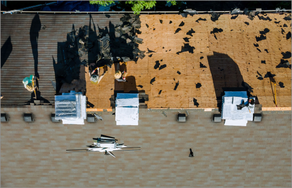 Aerial view of flood damaged roof with torn shingles and debris scattered around