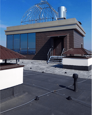 Modern observatory building with glass dome on rooftop against blue sky