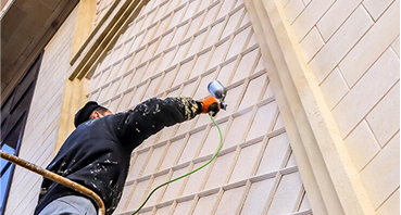 Professional window cleaner using squeegee on large commercial building windows