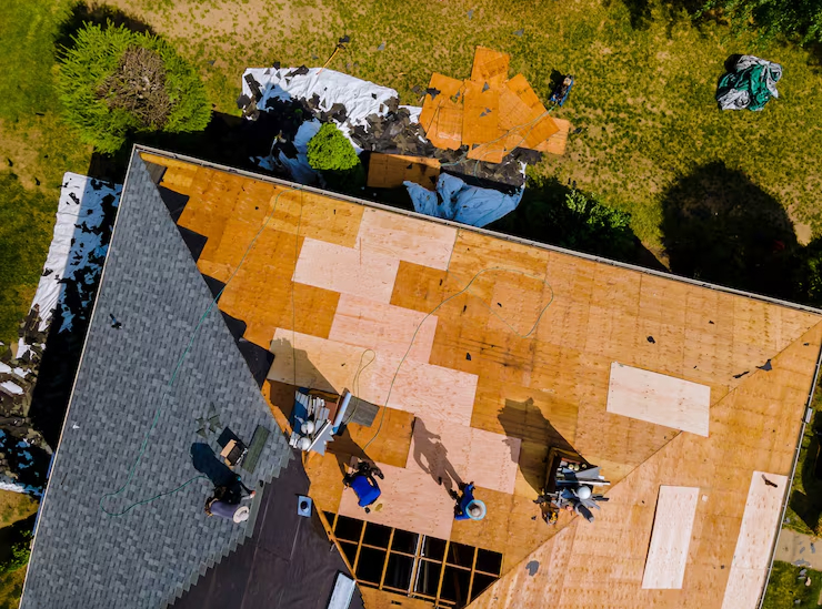 Aerial view of house roof construction with workers installing plywood sheathing