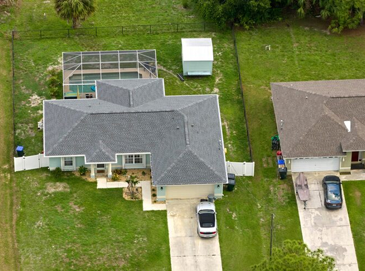 Aerial view of single-story home with pool and large backyard in residential area