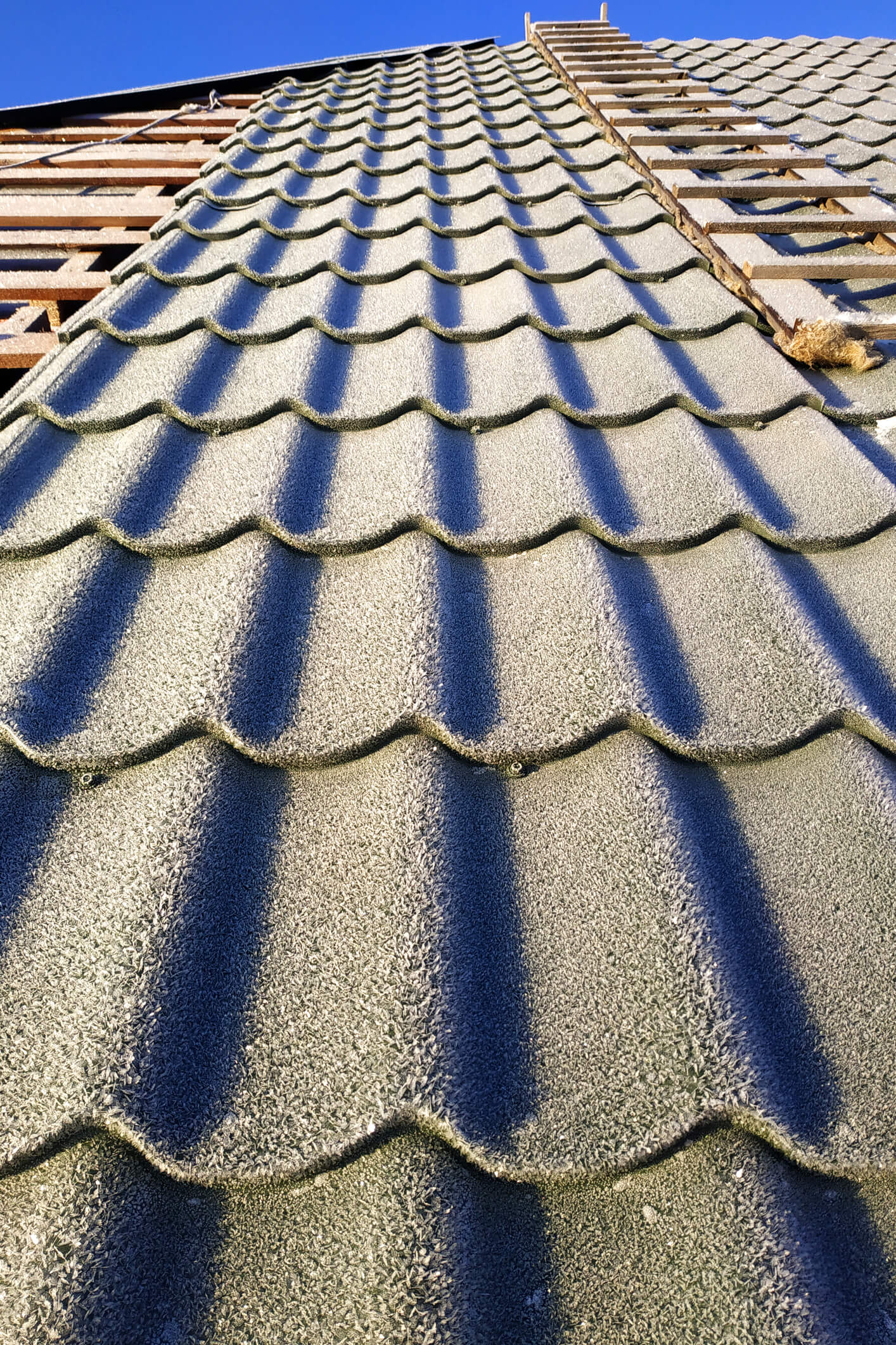 Clay roof tiles with dramatic shadows on residential rooftop under construction