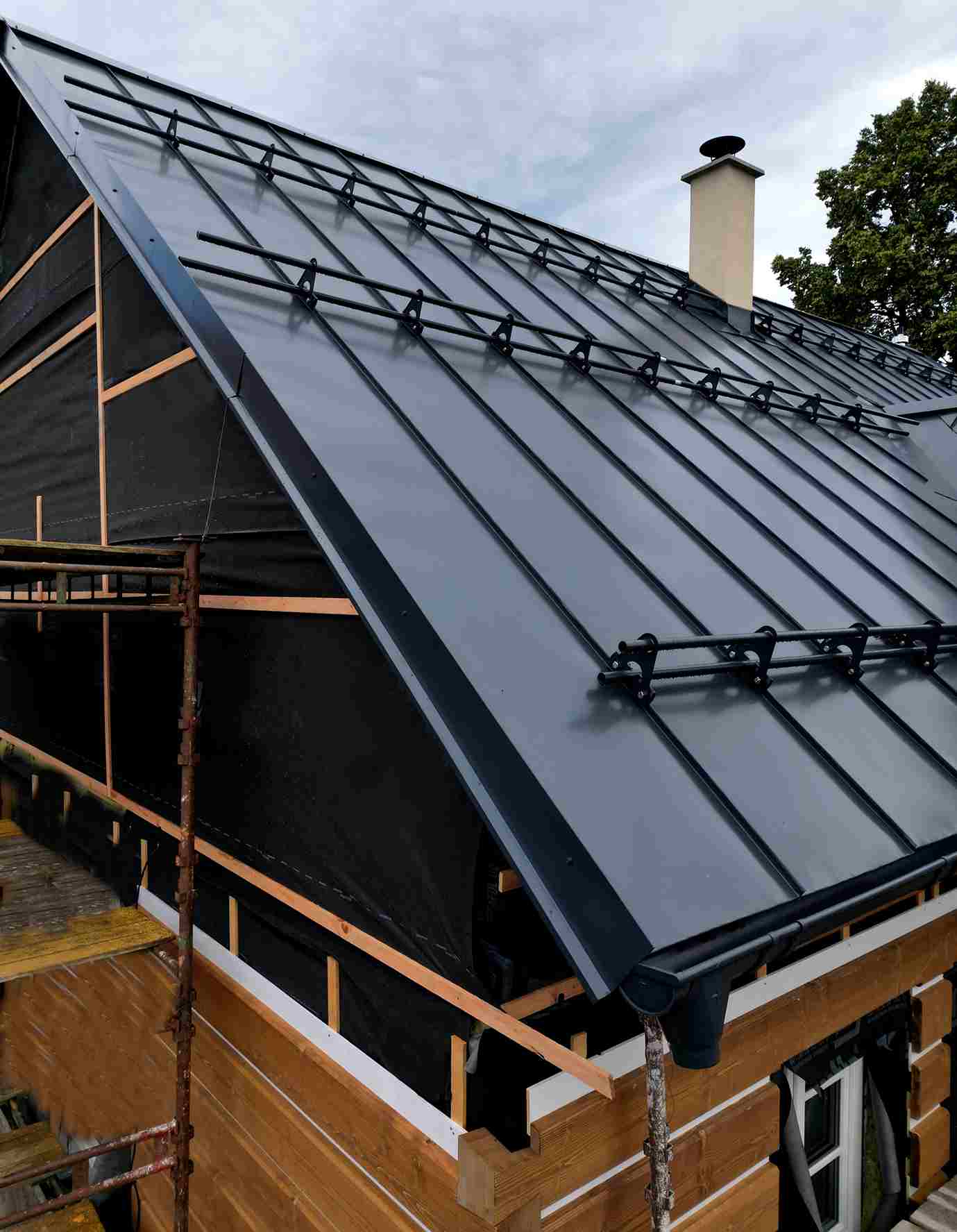 Metal roof installation with standing seam panels and snow guards on house
